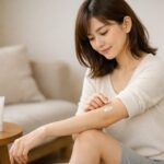 お風呂場で除毛クリームのパッチテストをしている日本人女性の腕のクローズアップ、赤みや刺激が出ないか静かに確認している様子, young Japanese woman in a bright bathroom gently patch testing hair removal cream on her forearm to check for irritation before full use